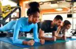 women and man in sportswear doing plank exercise on rubber mat in gym club. The concept of sports and recreation.